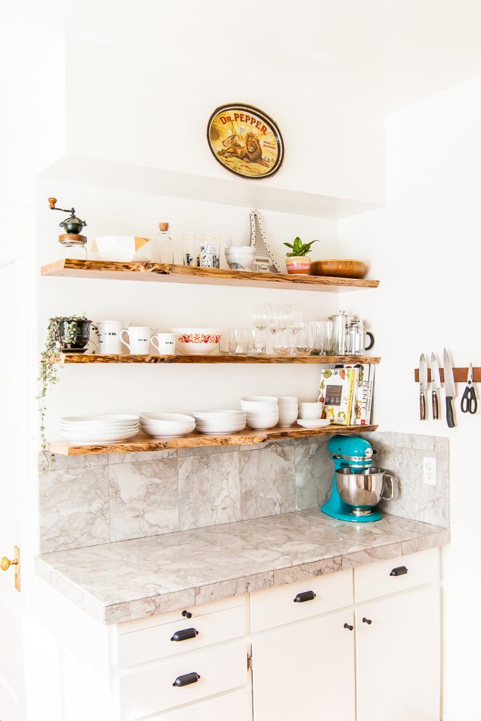 Kitchen makeover featuring white cabinets, and floating shelves made from live-edge wood. #kitchen #openshelves #DIY #openshelving